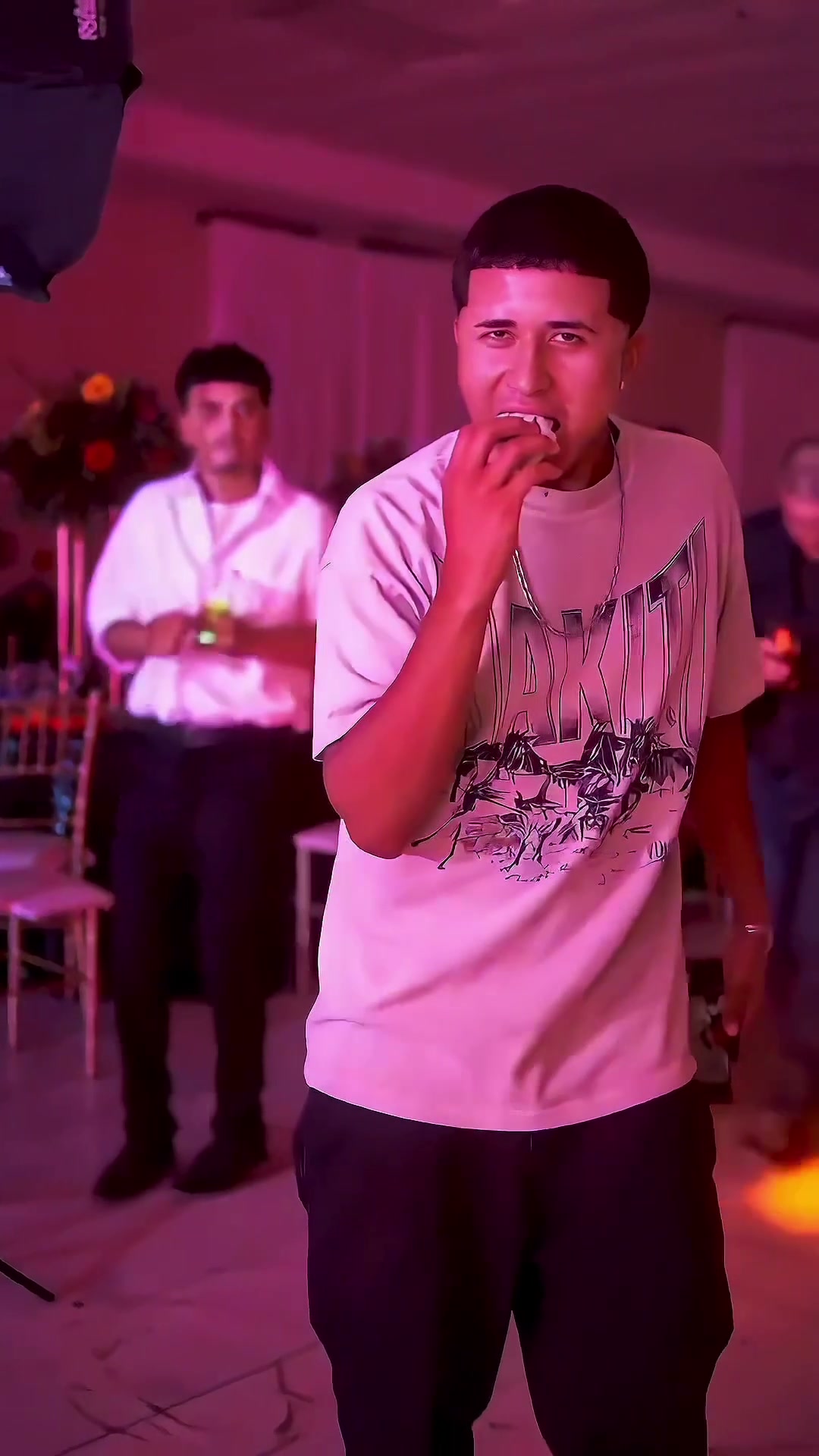 Reference frame of a party performer biting a round sweet bread near the camera